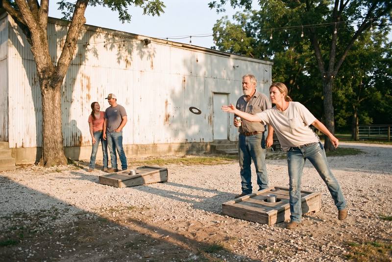 A woman pitching a steel washer toward the far washer box on the gravel, the gray-bearded man pitching against her waiting his turn beside her, the two players at the far box watching it come in.
